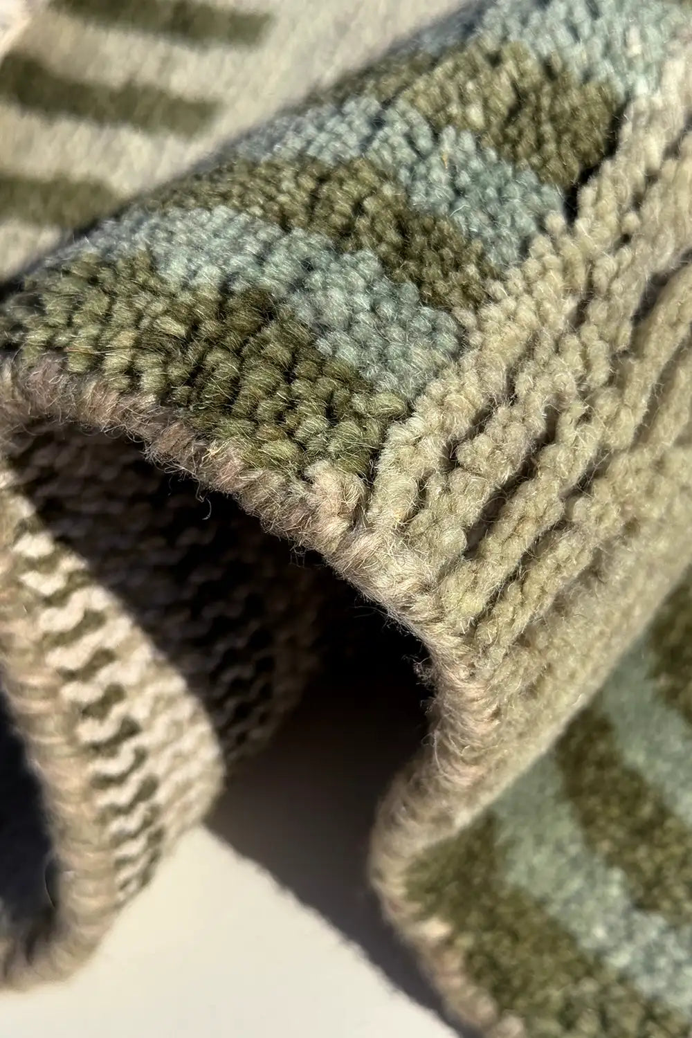 Close-up of a textured rug with a green geometric pattern