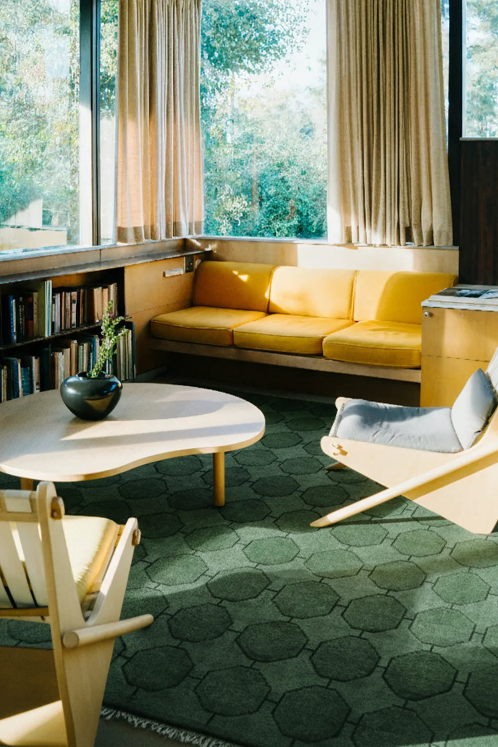 Modern living room with yellow sofa, green wool geometric rug, and large windows lifestyle