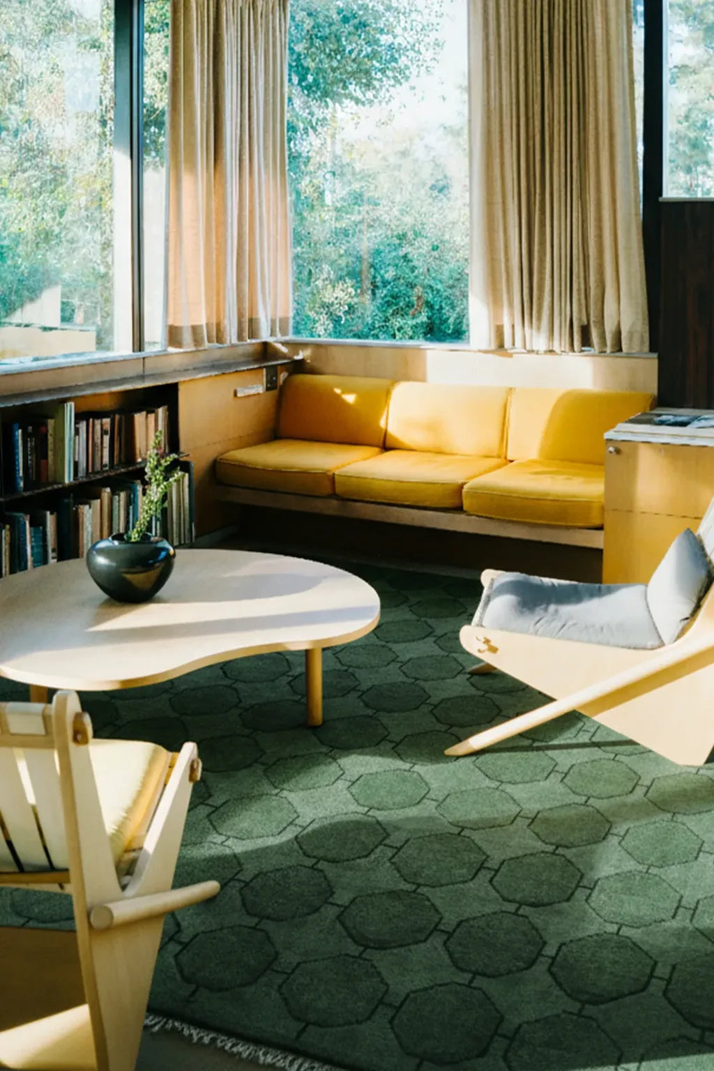 Modern living room with yellow sofa, green rug, and large windows lifestyle