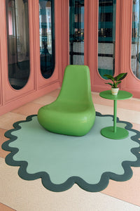 Green oval rug with dark scalloped edge in funky boho room, large wool area rug with ripple border design
