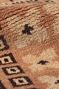 Handmade wool rug with small dark geometric accents on neutral background, ideal for modern and rustic decor