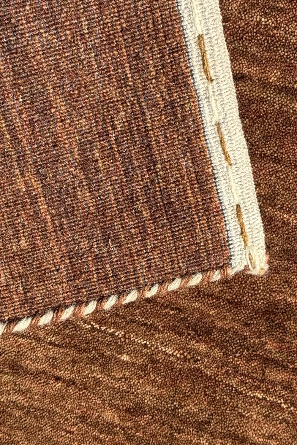 Close-up of warm brown luxury rug with white stitching detail chestnut