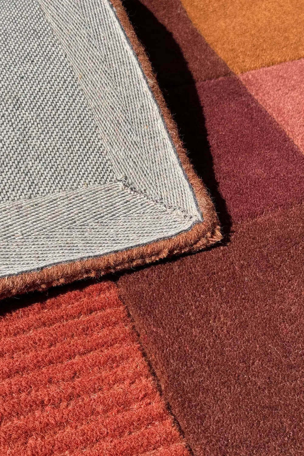 Close-up of terracotta hand-tufted modern wool rug with texture and warm hues, boutique 2x3 accent