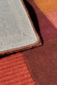 Close-up of terracotta hand-tufted modern wool rug with texture and warm hues, boutique 2x3 accent