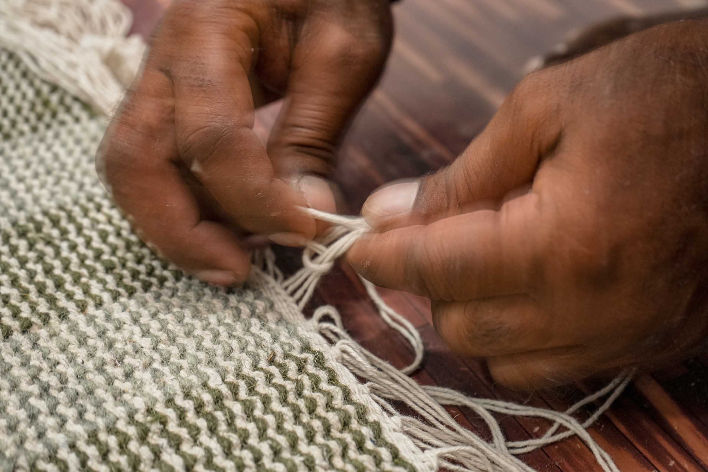 Artisan handweaving a Jubi rug on the loom in Bhadohi, India