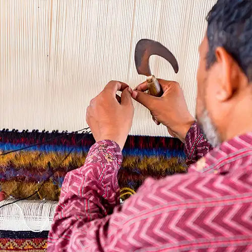 artisan at a loom handcrafting a modern custom rug in traditional knotting technique
