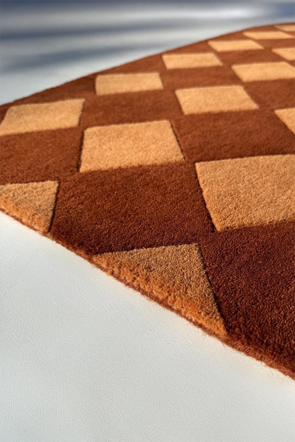 diamond patterned brown wool tufted rug shown up close with textured pile