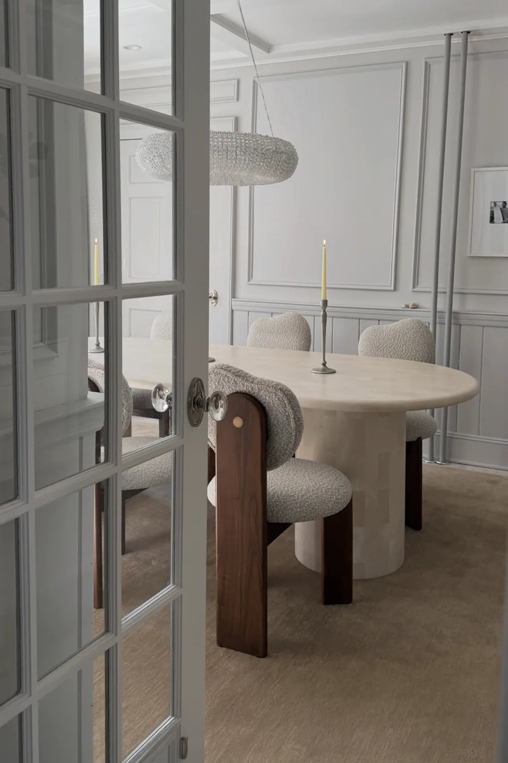 neutral rug stone dining room with a round table and chairs, viewed through a glass door.