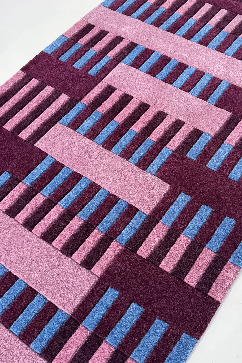 Geometric patterned rug with pink and blue lines on a white background