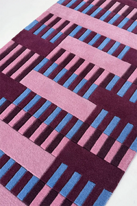 Geometric patterned rug with pink and blue lines on a white background