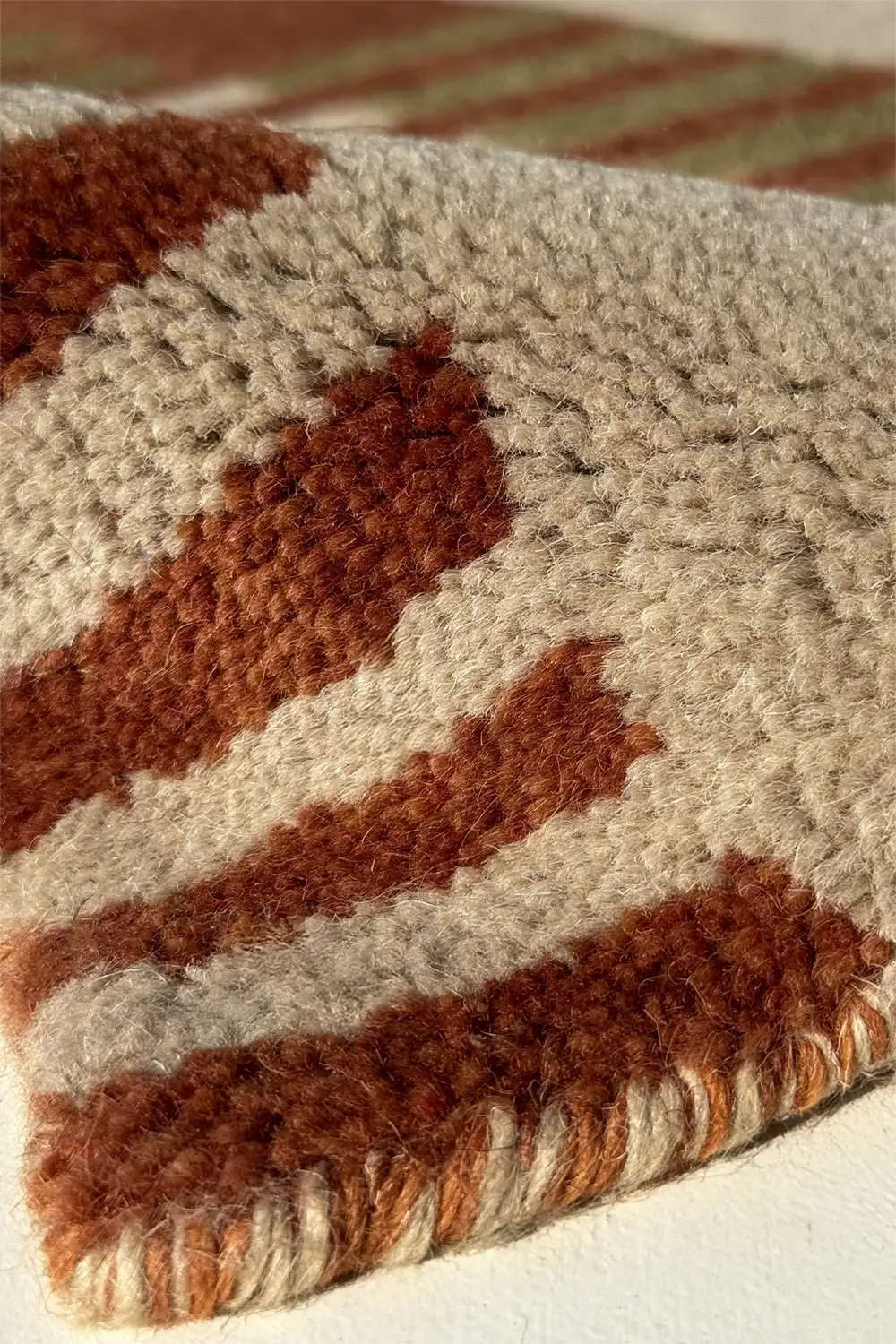 Close-up of a textured wool rug with rust brown and beige stripes multicolor