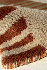 Close-up of a textured wool rug with rust brown and beige stripes multicolor