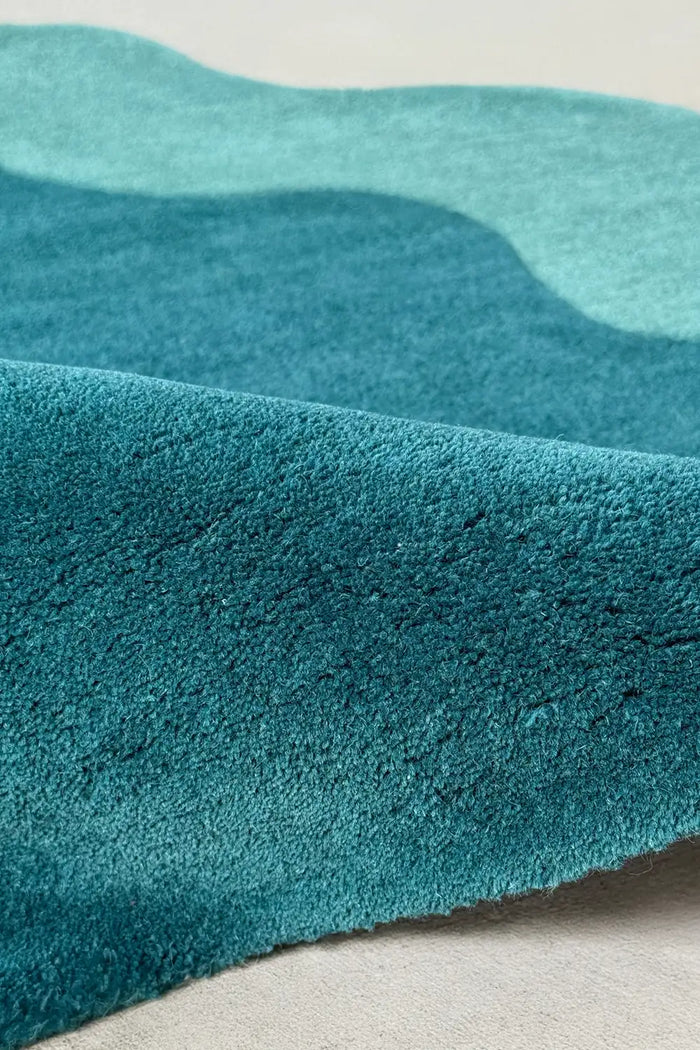 Close-up of deep teal wool pile in corner circle rug with a wavy abstract edge, perfect for modern living rooms or colorful entryways