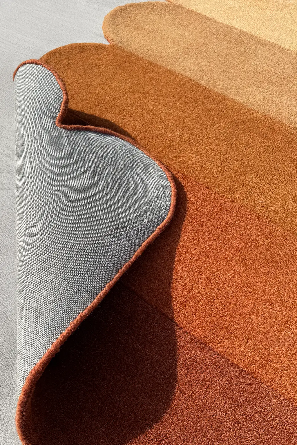 Custom scalloped area rug with cotton backing detail, in warm brown and orange for boho interiors