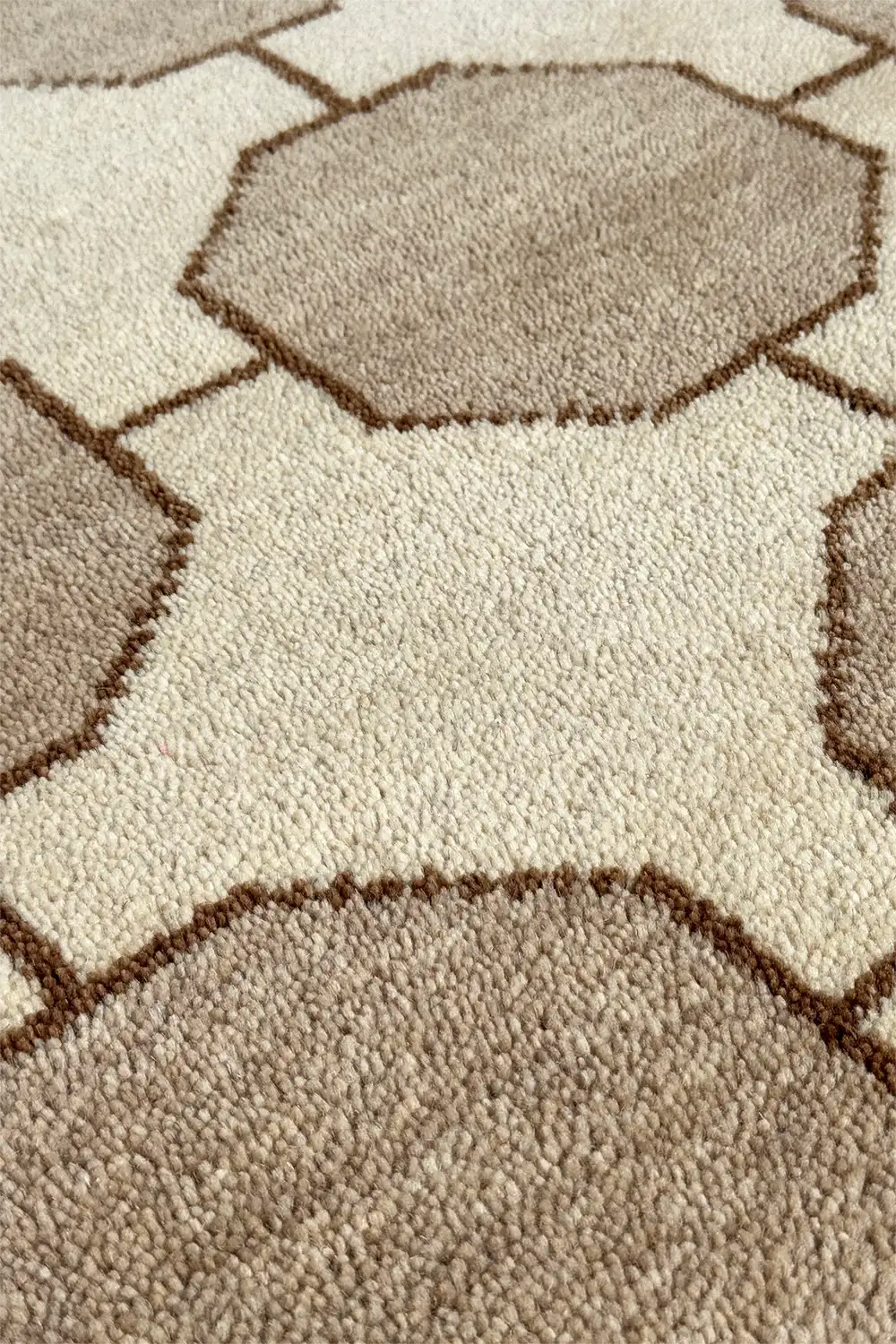 Close-up of a large textured beige and brown area rug with geometric pattern ivory