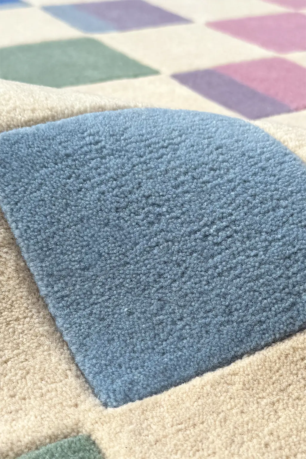 Close-up of a textured pastel blue rug with geometric checkerboard pattern