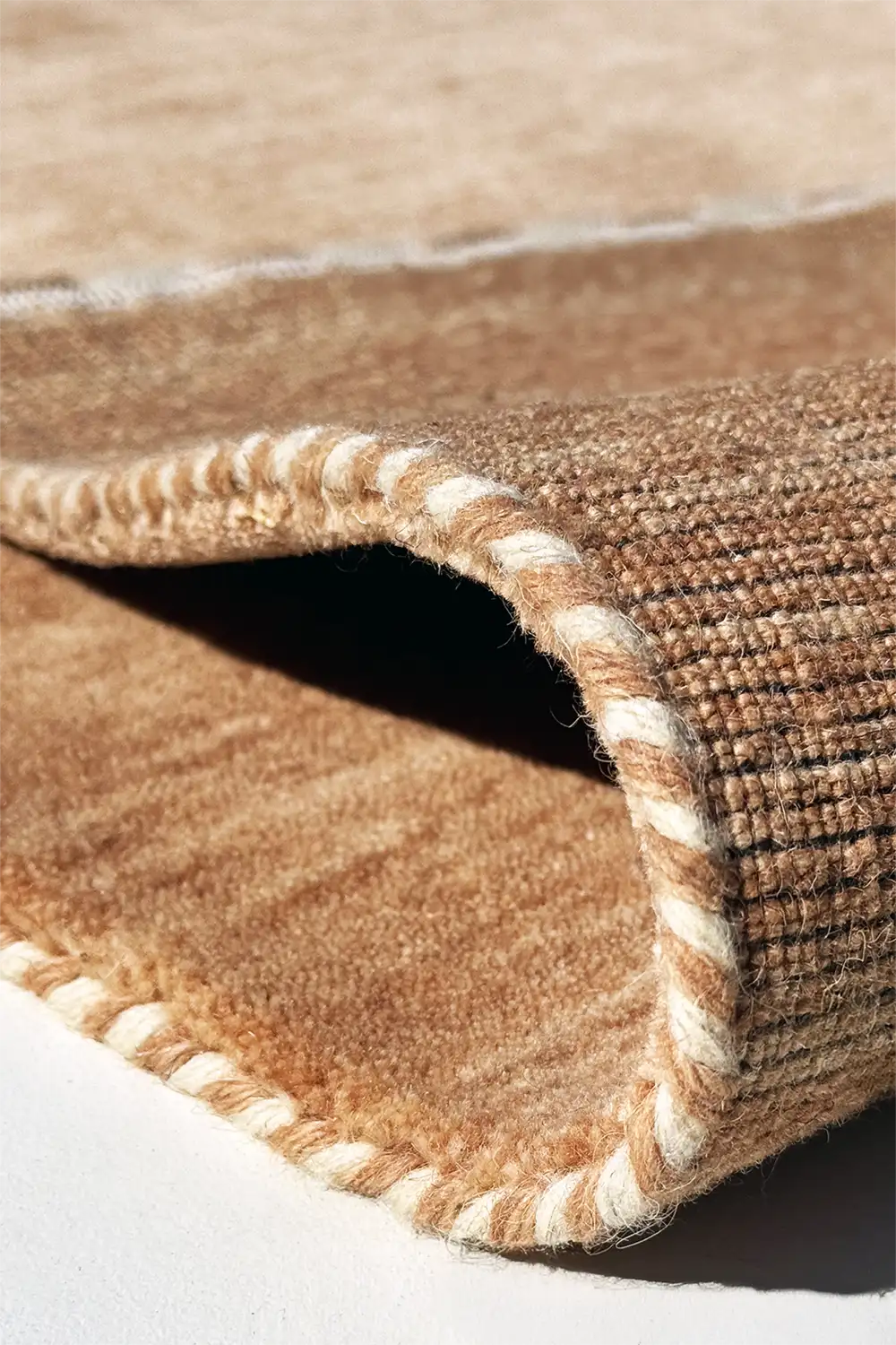 Close-up of a brown textured rug with a white border.