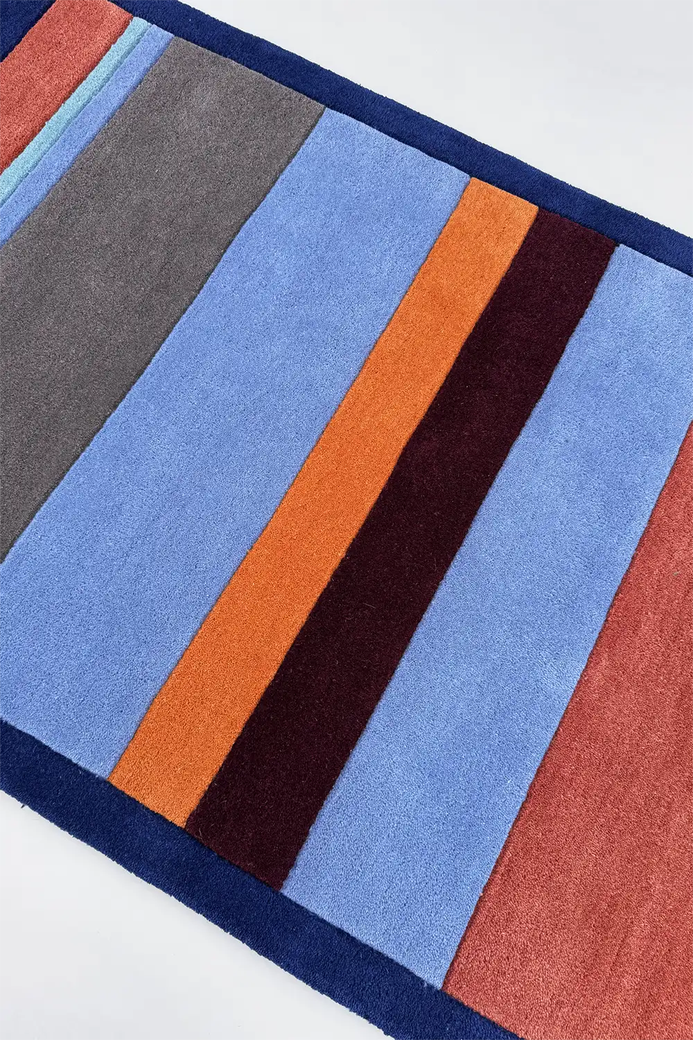 Colorful striped rug with blue, orange, and red stripes on a white background