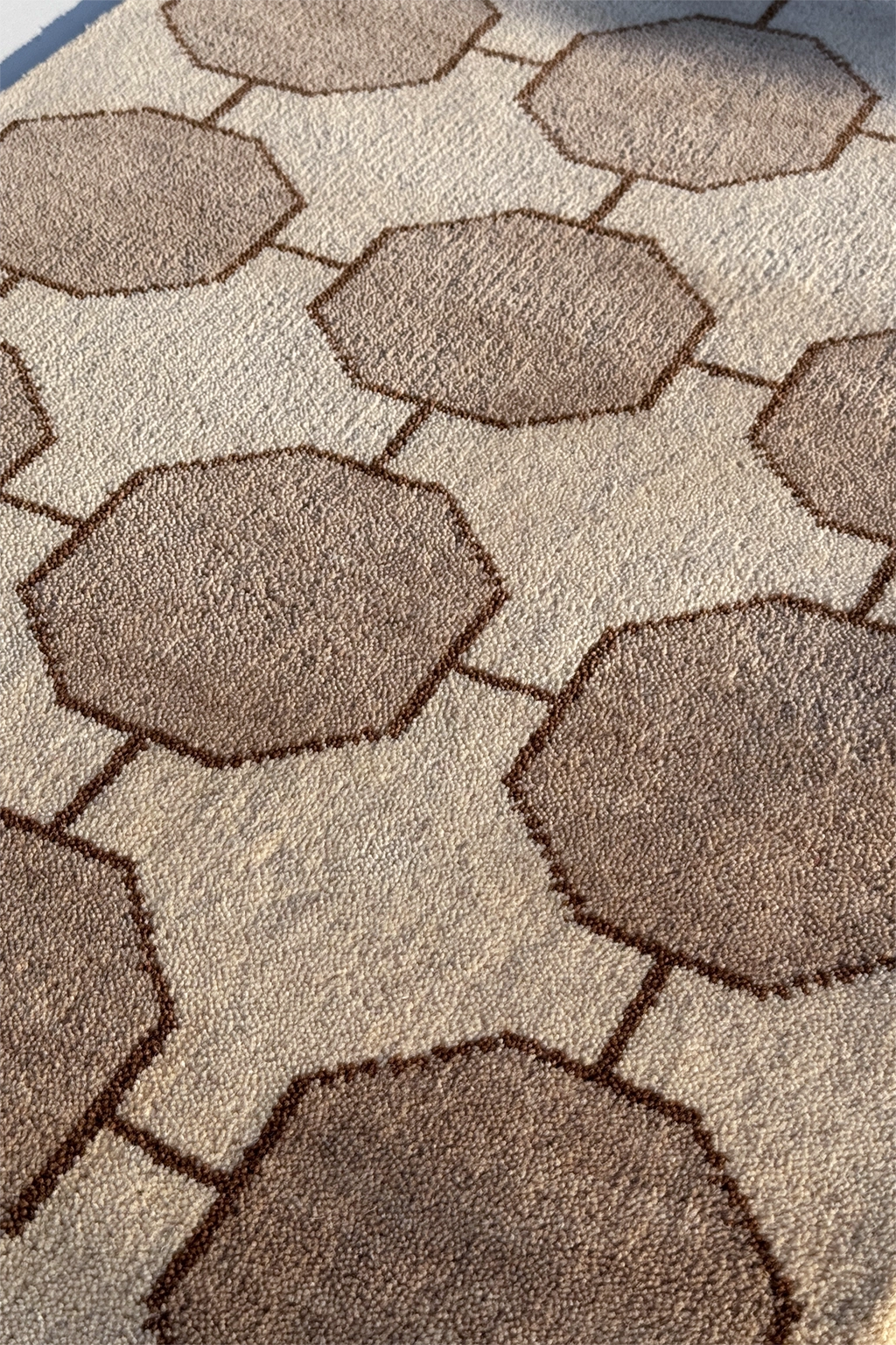 Close-up of a textured ivory and beige wool area rug with geometric pattern