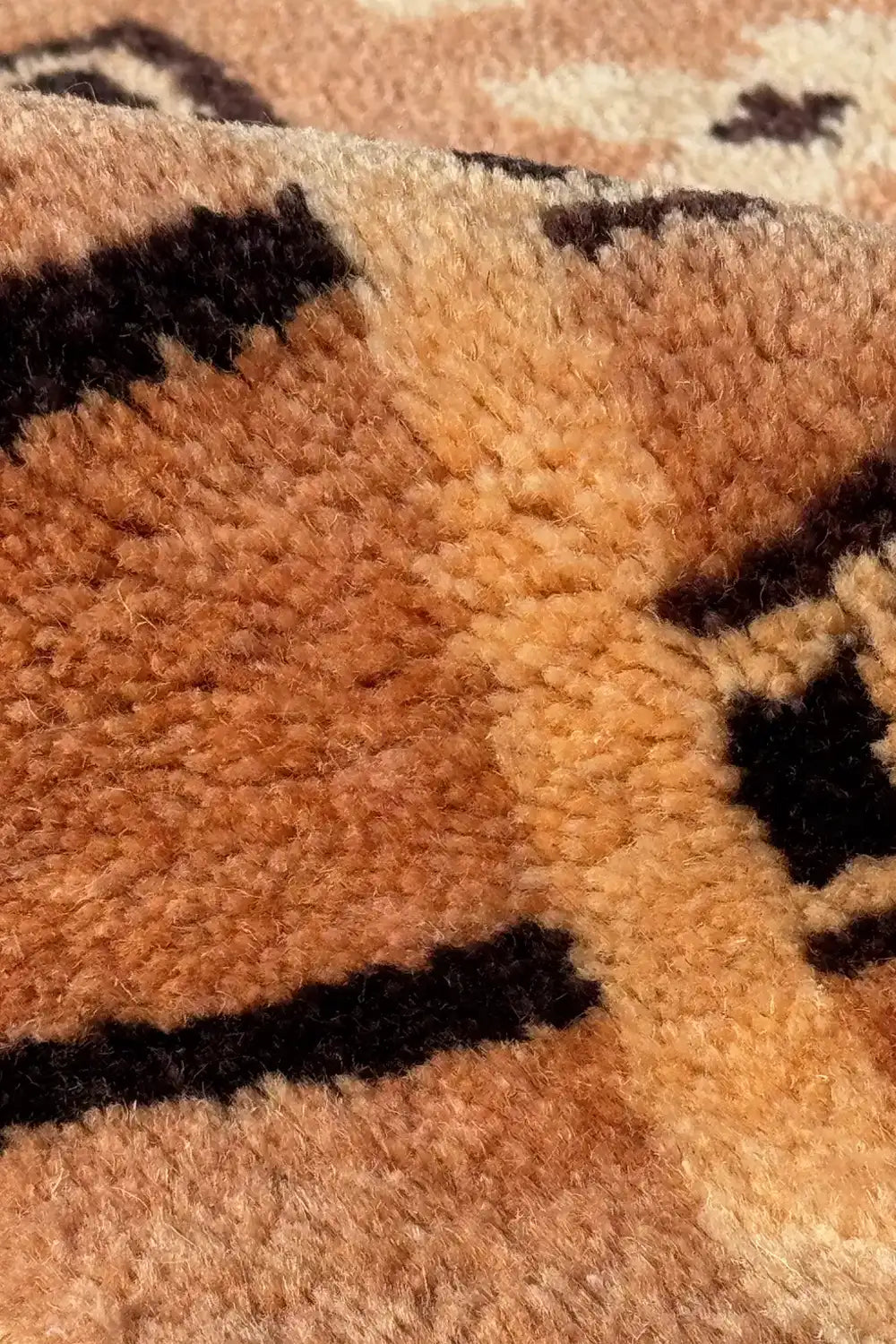 Detailed view of hand knotted mid-century square rug with small motifs and warm brown tones, wool texture visible