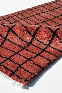 rust rug with black geometric pattern on a white background