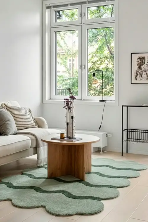 Living room with a green wavy rug, wooden coffee table, and white sofa.