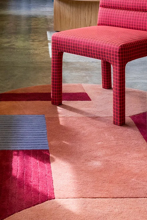 Red checkered chair on a textured pink and red rug in a modern designer room