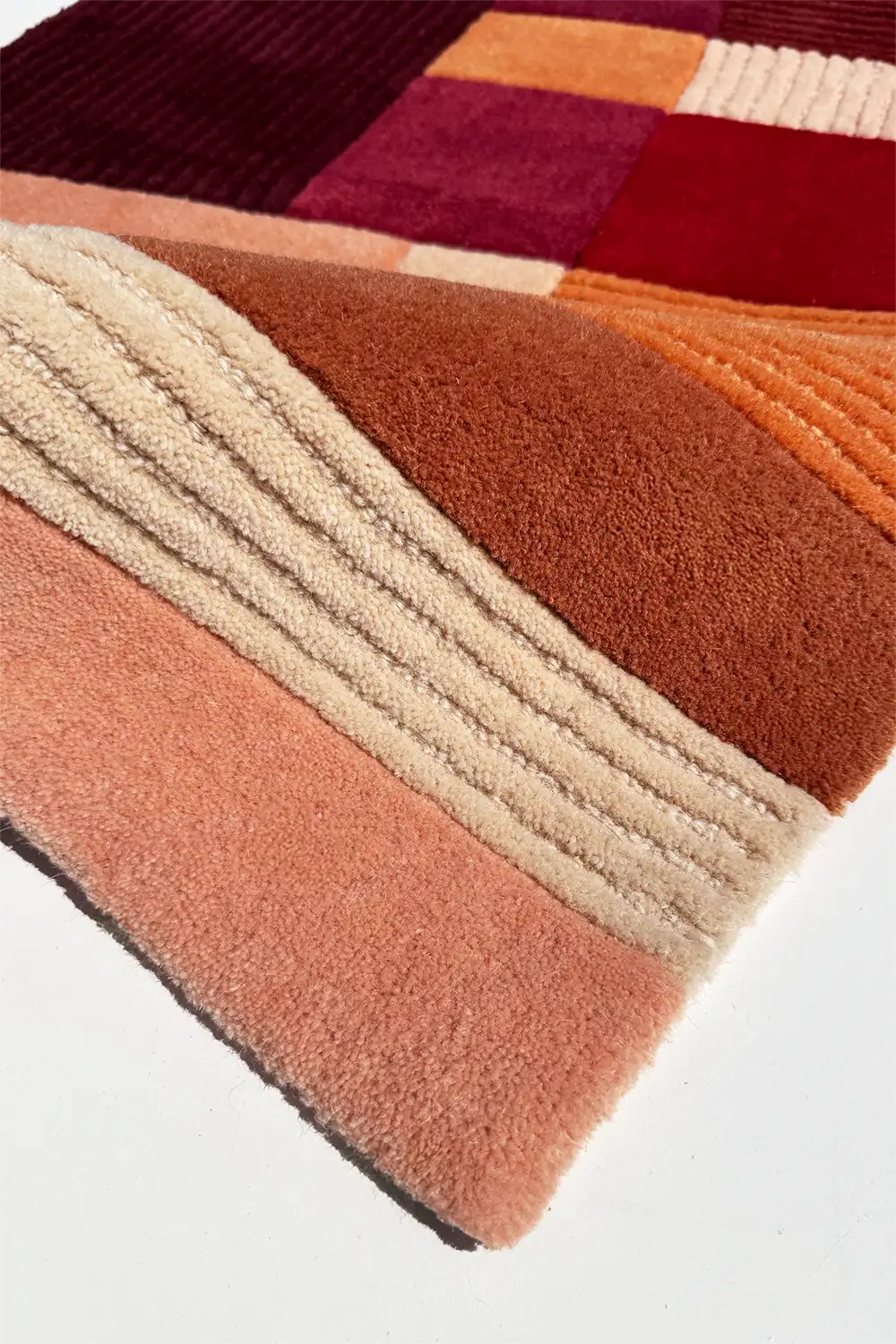 Multicolored geometric patterned rug with shades of red, orange, and beige.