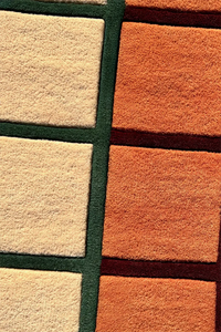 Close-up of a multicolor runner rug with square patterns in beige, orange, and green.