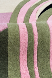 Close-up of a multicolor wool rug with pink and green texture stripes on a neutral background