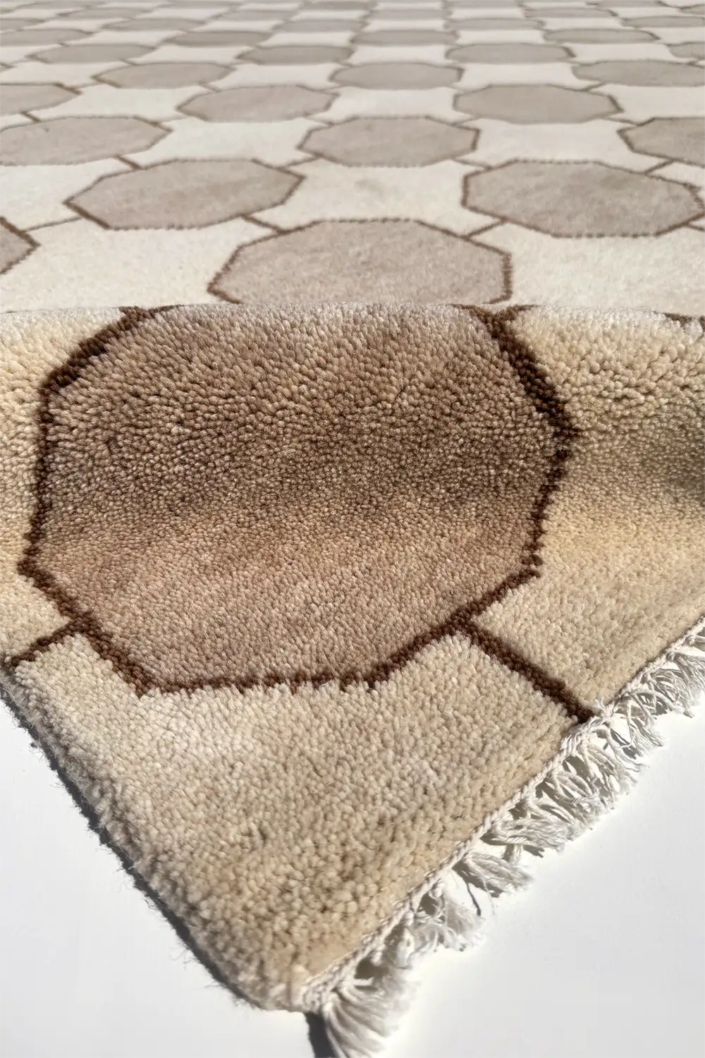 octagonal patterned wool rug with fringe on a tiled floor ivory