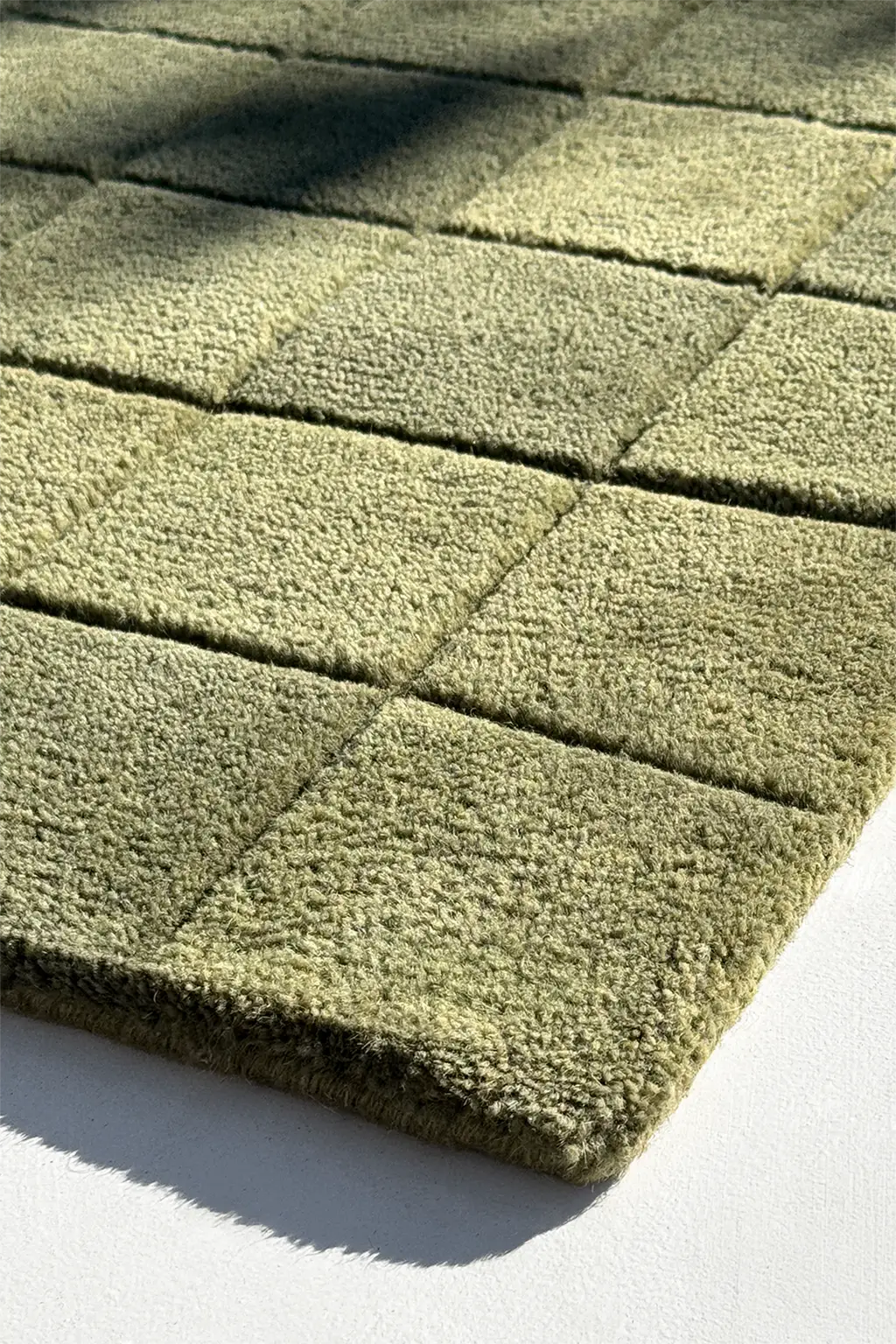 Close-up of a light green textured rug with geometric pattern
