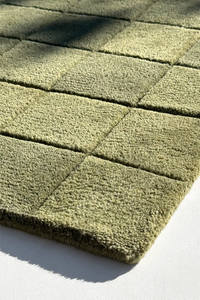 Close-up of a light green textured rug with geometric pattern