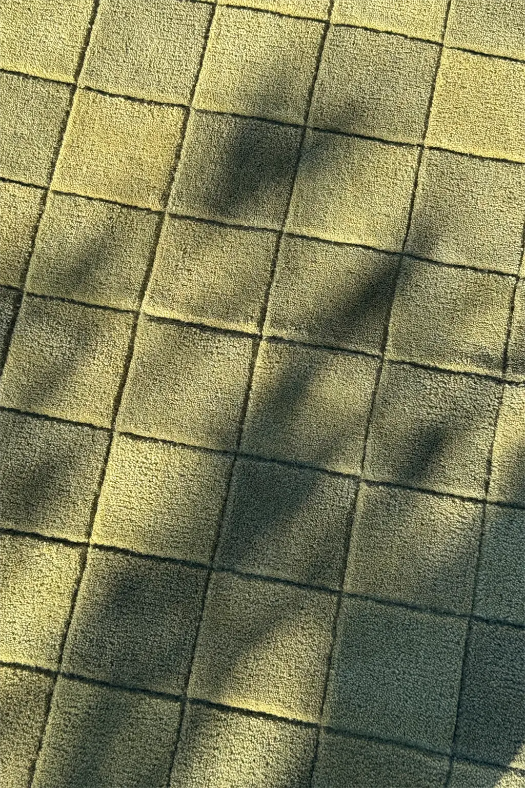 Close-up of olive rug with tonal checkerboard pattern