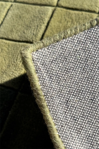 Close-up of a textured green checkered rug with serged edges