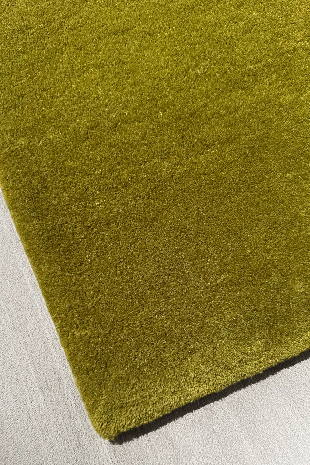 Close-up of a green textured rug corner on a white background