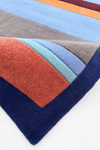 Colorful geometric-patterned rug with a mix of red, blue, orange, and gray on a white background lifestyle