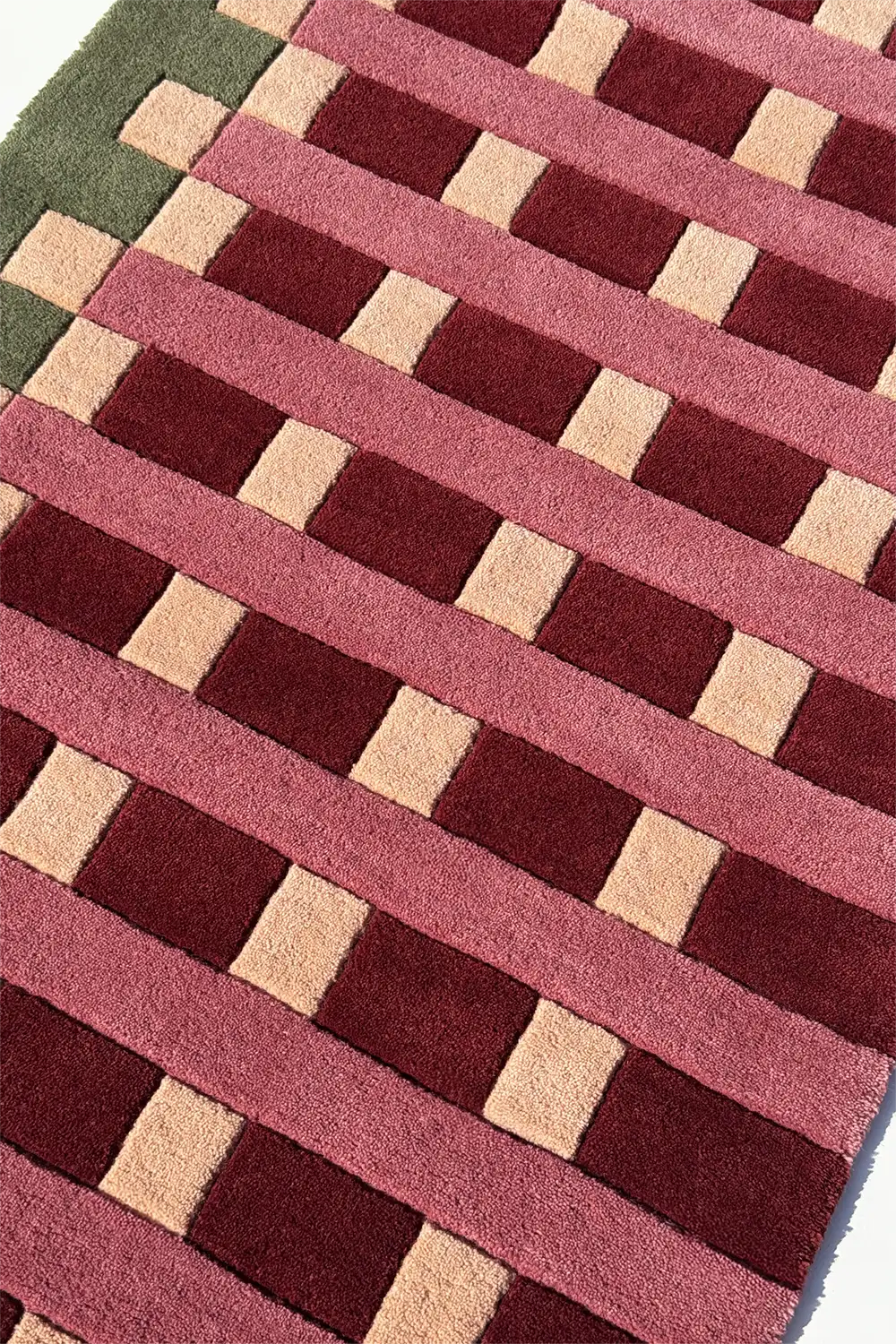 Close-up of a patterned long runner rug with red, beige, and green stripes.