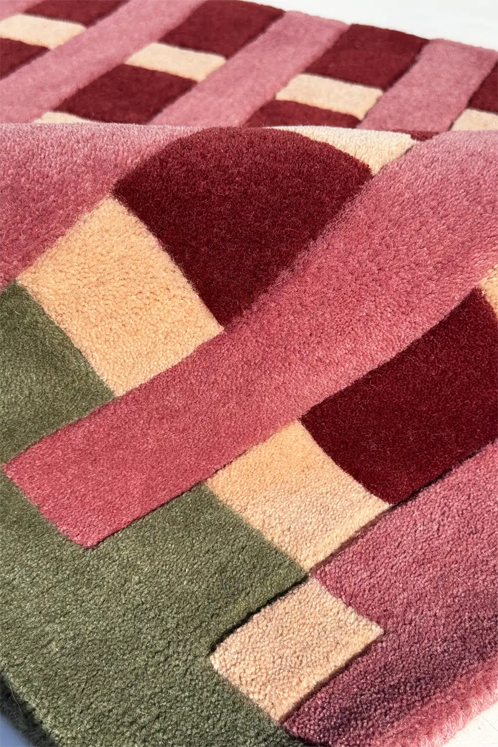 close up view of colorful geometric-patterned rug with pink, red, and green stripes.