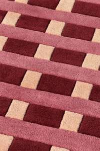 pattern detail of geometric square rug with red cream and pink stripes
