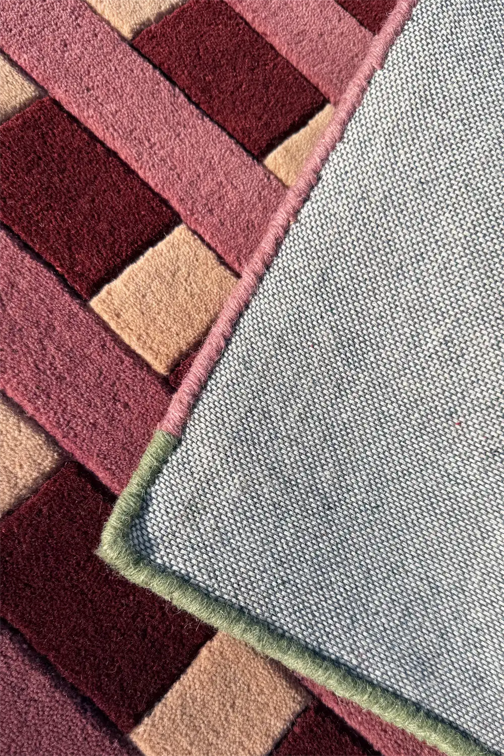 Close-up of a textured rug with geometric pattern in red, beige, and gray backing.