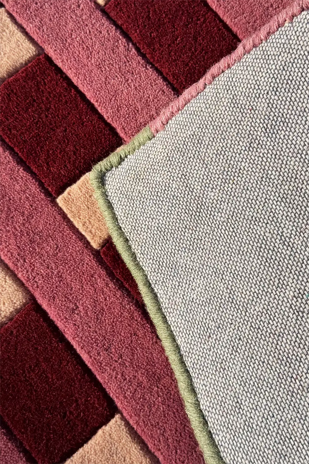 Close-up of a textured rug with geometric pattern in reds and creams.