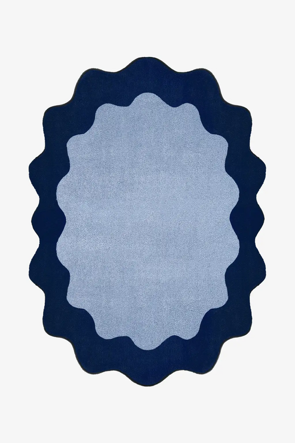 oval blue rug with navy scalloped edge on a white background
