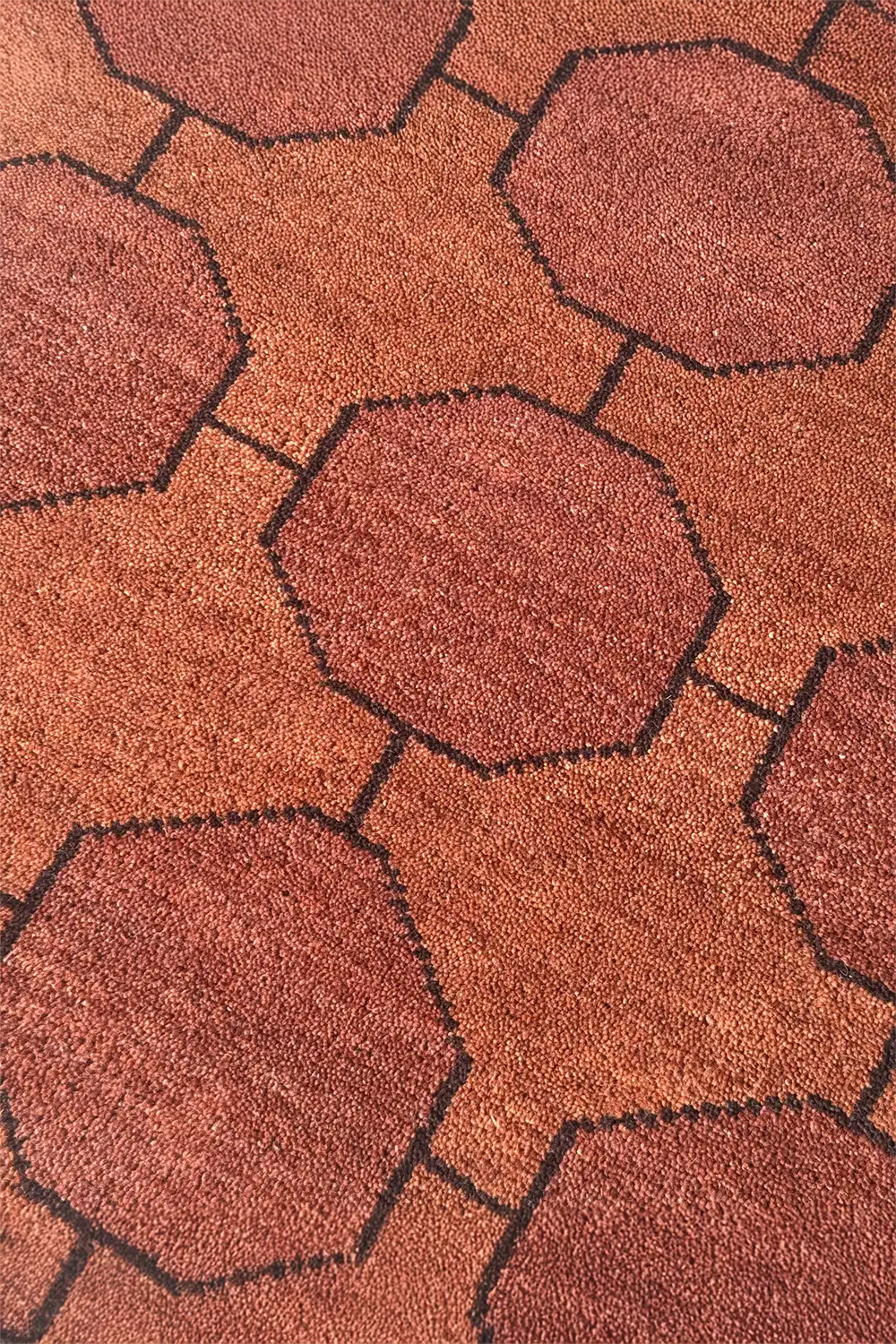 Close-up of a textured chestnut brown graphic rug with geometric patterns