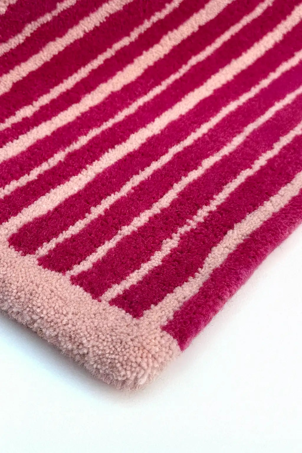 Close-up of a colorful pink and blush striped rug with a white background