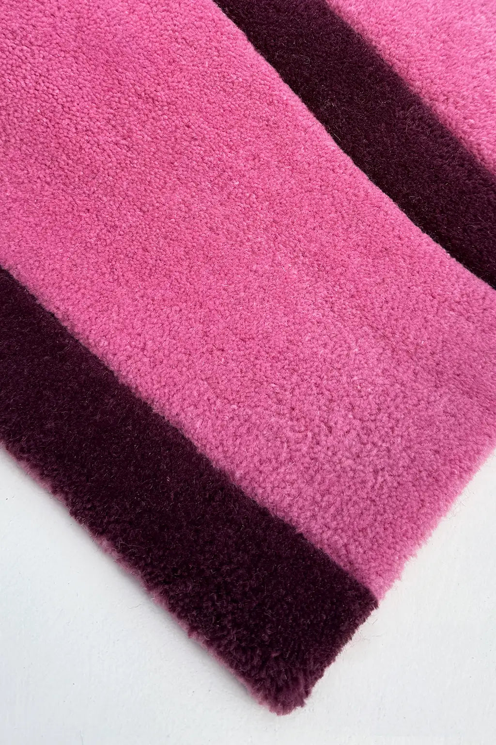 Close-up of pink and purple striped rug corner on a white background