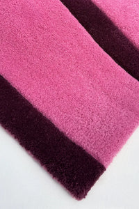 Close-up of pink and purple striped rug corner on a white background