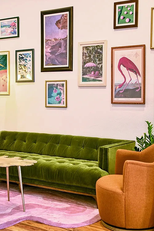 Green sofa in a room with colorful wall art and a pink rug.