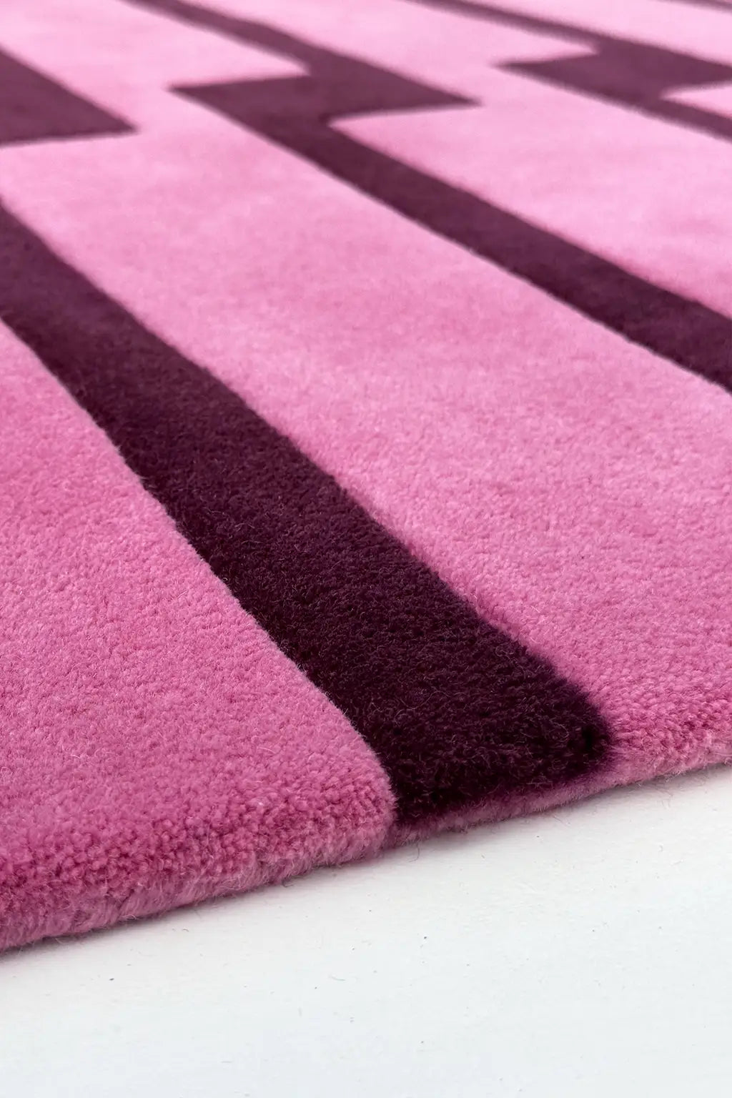 Close-up of a pink and purple striped tufted wool rug texture