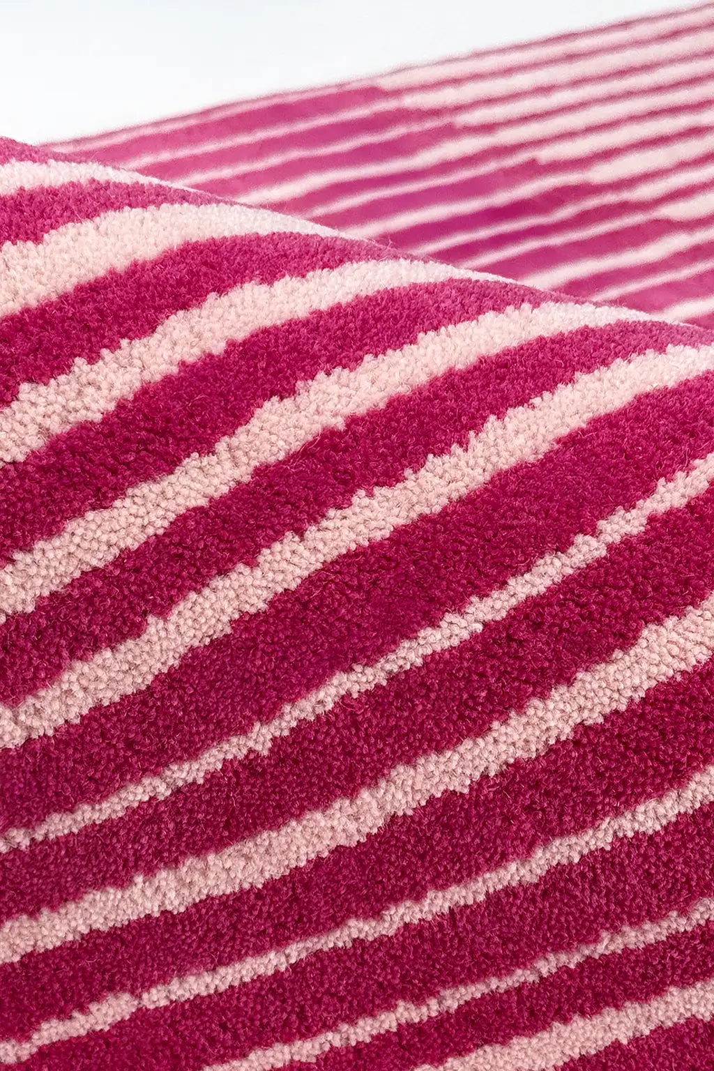 Close-up of a textured rug with pink and white stripes.
